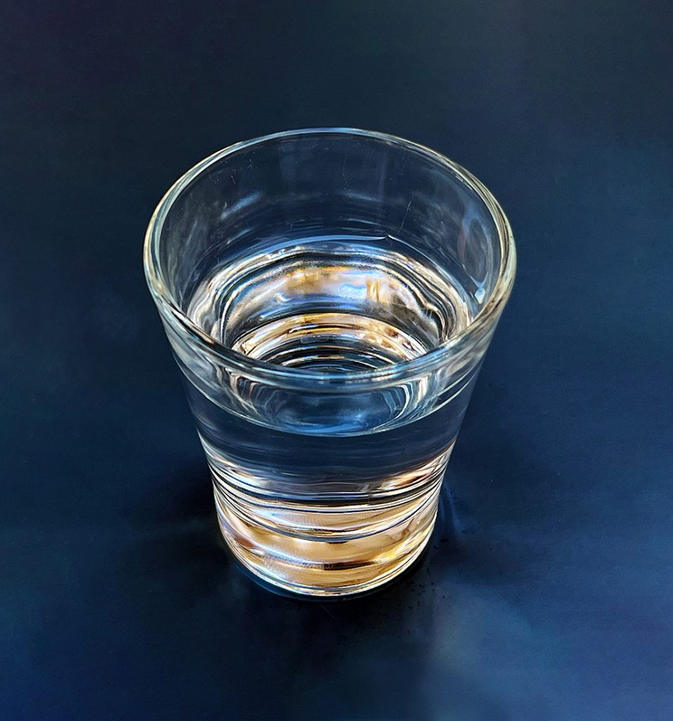 Ein schlichtes Wasserglas steht auf einem dunklen Cafétisch. Sonnenlicht durchdringt Glas und Wasser und erzeugt leuchtende blaue und goldene Reflexe sowie fließende Formen. Ein unscheinbarer Alltagsmoment verwandelt sich durch aufmerksames Sehen in etwas überraschend Schönes.
A simple glass of water rests on a dark café table. Sunlight passing through the glass creates vivid blue and golden reflections with soft, flowing shapes. An ordinary moment reveals unexpected beauty when seen with quiet attention.